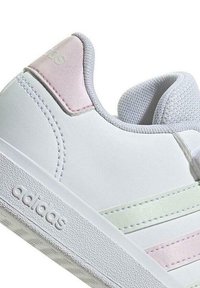 Sneaker bianco con accenti rosa e verde chiaro. Realizzato in materiale sintetico liscio, presenta una suola testurizzata e un logo sul lato.