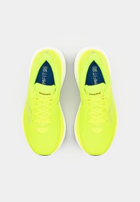 Neon-gelbe Laufschuhe mit einem Mesh-Obermaterial, flachen Schnürsenkeln und einer gepolsterten weißen Sohle. Mit kontrastierendem blauen Innenfutter und Logo.