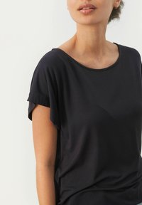 Must-haves lühikeste varrukatega must topp, millel on mugav lõige ja ümmargune kaelus. Sile tekstuur, kergest kangast ning õrn drapeeringu detail.