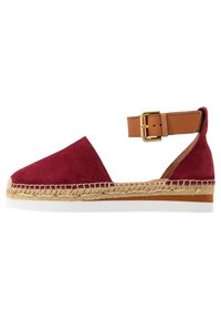 Sandale espadrille en daim rouge avec une sangle à la cheville en cuir tanné et une boucle dorée, ornée de garnitures en jute et d'une semelle en caoutchouc blanc.