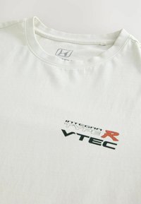 Hvid bomulds t-shirt med rund hals, prydet med et sort og rødt grafisk design, der står "INTEGRA TYPE R VTEC" på forsiden. Glat tekstur.