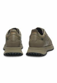 Olivgröna lädersneakers med texturerad yta, vadderad sula och kontrasterande svart yttersula, med subtil branding på hälen.
