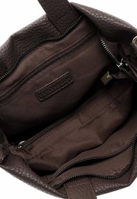 Innenansicht einer braunen Lederhandtasche mit strukturierter Oberfläche, mehreren Reißverschlussfächern und einem Stofffutter. Sichtbare Ziernähte.