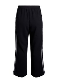 Čierne široké nohavice s elastickým pásom a dvoma bielymi pruhmi na bokoch, ktoré vedú vertikálne pozdĺž každej nohy.
