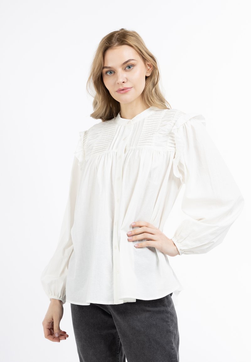 Witte blouse met knoopsluiting aan de voorkant, geplooide schouders en opgeblazen mouwen. Zacht materiaal met een relaxed fit en afgeronde zoom.
