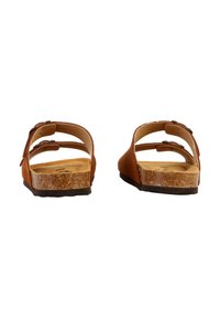 Sandales en daim marron avec deux sangles ajustables, une semelle en liège et une semelle en caoutchouc plate et basse. Présentant un design simple, à dos ouvert.