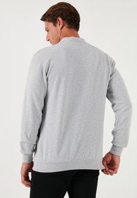 Suéter gris claro, tela de punto, puños y dobladillo acanalados, mangas largas, diseño de cuello básico, textura suave, estilo minimalista sin patrones.