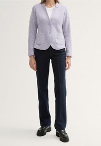 Lila ullblandad kavaj med två framfickor och rundad nederkant, kombinerad med mörkblå raka jeans och svarta platåskor.