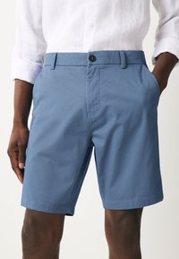 Moške svetlo modre kratke hlače iz gladkega blaga, s zapenjanjem na gumbe, stranskimi žepi in ravnim krojem.