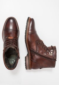 Brązowe skórzane botki za kostkę o fakturowanym wykończeniu, okrągłym nosku, sznurowanym przodzie, zamku błyskawicznym z boku oraz gumowej podeszwie z drewnianymi akcentami.