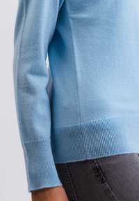 Ljusblå tröja i mjuk stickad kvalitet, med en figurnära design, ribbade muddar och fåll för extra textur och detaljer.