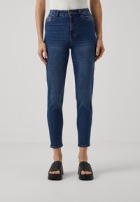 Jeans de mezclilla azul de cintura alta con un ajuste slim, que cuentan con un cierre de botón en la parte frontal, cinco bolsillos y un leve desvanecimiento en los muslos.