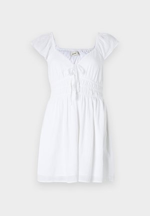 Fehér ruha rövid, puffos ujjakkal, V-nyakkivágással és gumis derékkal, elöl megkötő díszítéssel és folyó szoknyával.
