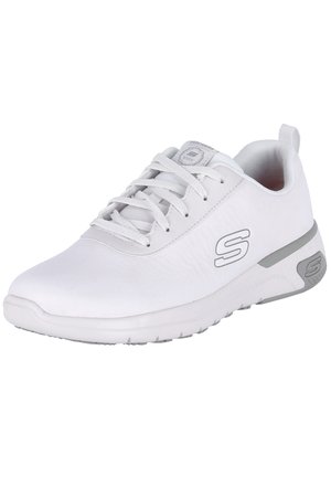 Chaussure de sport blanche avec une tige en synthétique lisse, un design à lacets et des accents argentés sur le logo et la semelle extérieure. Bout arrondi et semelle en caoutchouc.