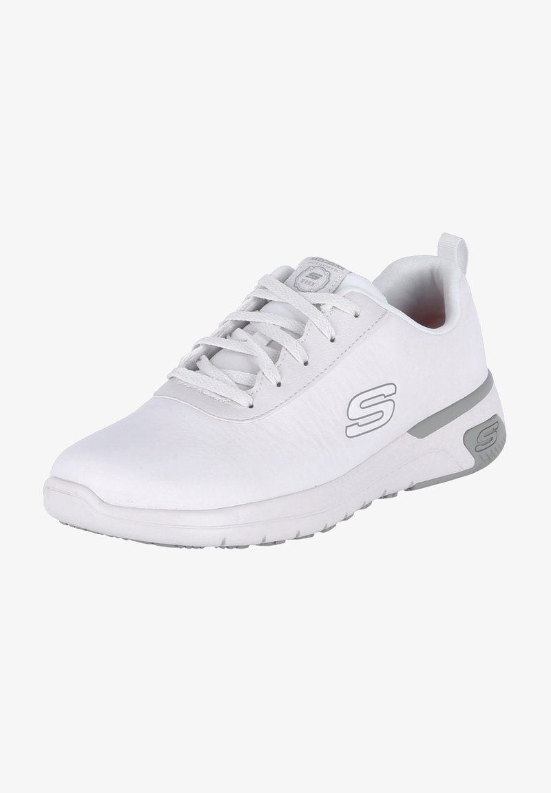 Chaussure de sport blanche avec une tige en synthétique lisse, un design à lacets et des accents argentés sur le logo et la semelle extérieure. Bout arrondi et semelle en caoutchouc.