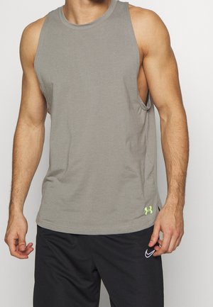 Man draagt een grijs mouwloos Under Armour-shirt en zwarte Nike-short tegen een effen witte achtergrond.