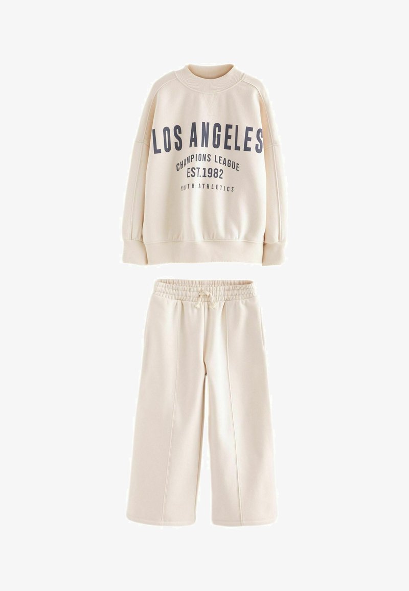 Kremowy sweatshirt z granatowym napisem "LOS ANGELES CHAMPIONS LEAGUE EST.1982", w połączeniu z pasującymi spodniami dresowymi z elastycznym pasem.
