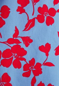 Motif floral rouge vif avec des feuilles sur un fond en tissu texturé bleu clair.