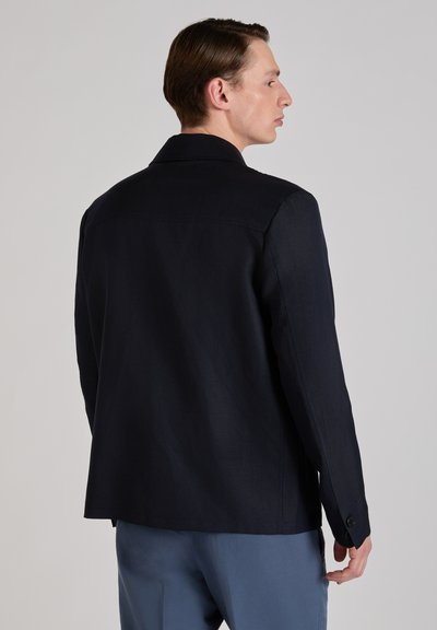 Dunkelblaue Jacke mit sauberem, strukturiertem Design. Verfügt über einen klassischen Kragen, knöpfbare Ärmelbündchen und eine glatte Stoffstruktur.