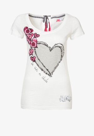 Camiseta blanca de manga corta con un gran corazón delineado, varios corazones pequeños rosas a la izquierda y el texto "la vida es chula."