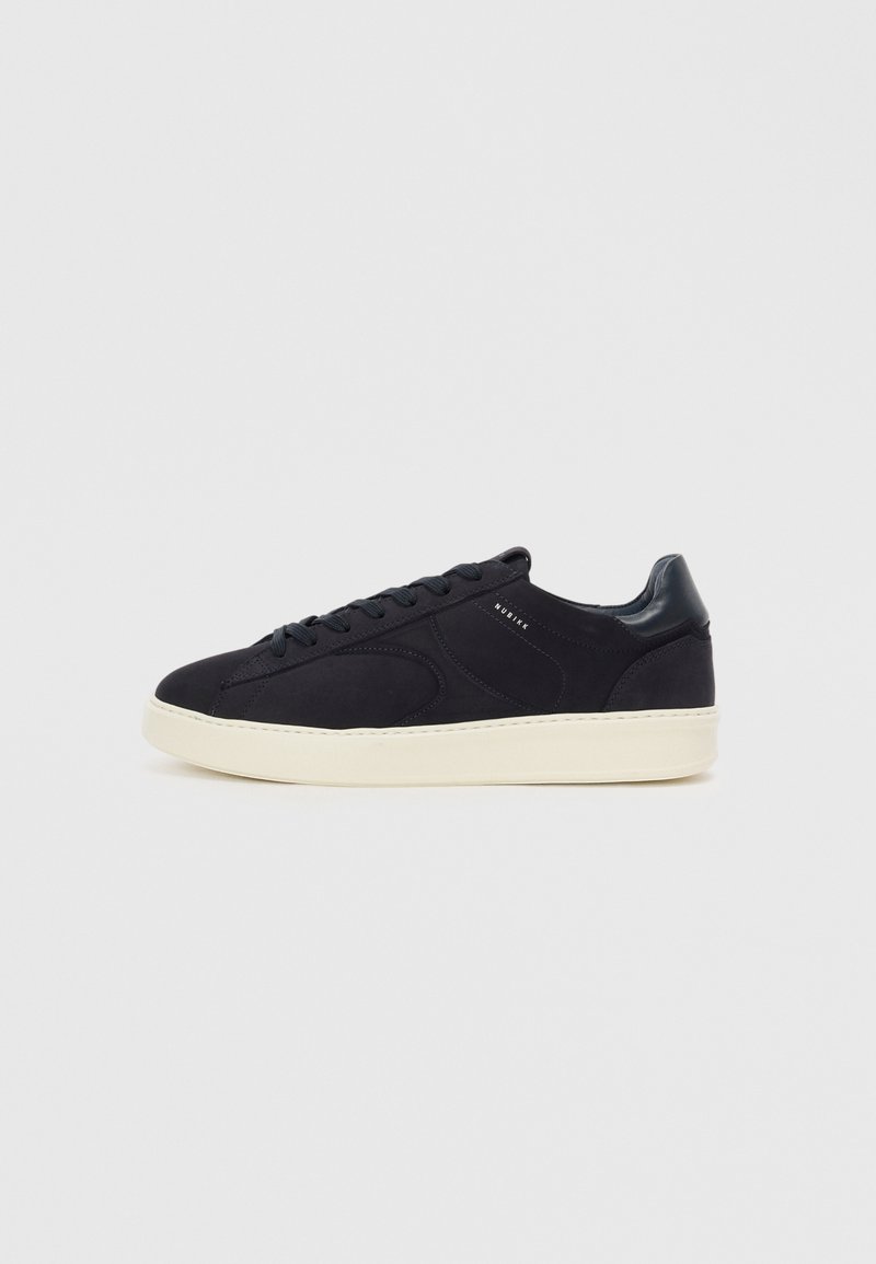Sneaker nera in suede con cuciture tono su tono, punta rotonda, lacci piatti e suola in gomma color crema. Presenta un accento sul tallone glossy nero.