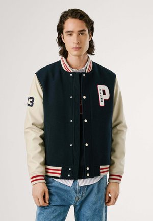 Chaqueta varsity de mezcla de lana en color marino con mangas de cuero beige, cuello a rayas rojas y blancas, número 13 y letra P bordada.