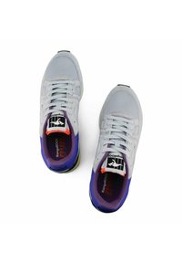 Scarpe sportive grigio chiaro con accenti viola e tomaia in rete. Le caratteristiche includono una punta rotonda, chiusura con lacci e etichette con il marchio sulla linguetta.