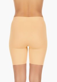 Beige, zökkenőmentes sort, sima textúrával és középmagas szárhosszal, rugalmas derékkal a kényelem és a stabilitás érdekében.