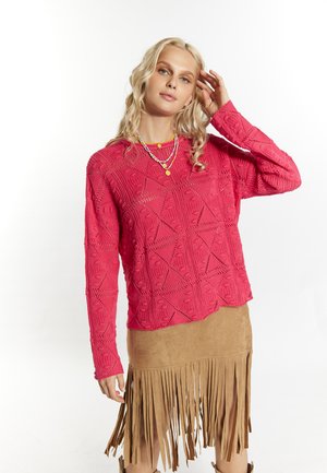 Pulover roz tricotat cu un model geometric și mâneci lungi, împairat cu o fustă din suede cu franjuri în nuanța bej.
