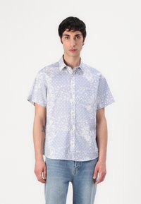 Camicia a maniche corte con colletto in tessuto azzurro chiaro, decorata con motivi floreali e a pois, dotata di taschino sul petto e chiusura con bottoni.