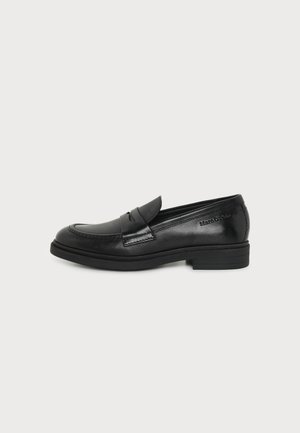 Μαύρο δερμάτινο loafer με χαμηλό τακούνι και ραμμένες λεπτομέρειες, με λουρί στο πάνω μέρος και ανάγλυφο λογότυπο στο πλάι.