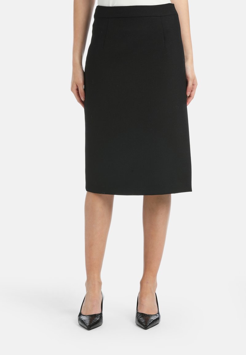 Black pencil skirt with a smooth texture, knee-length design, and subtle front pleats. Paired with pointed-toe black pumps.