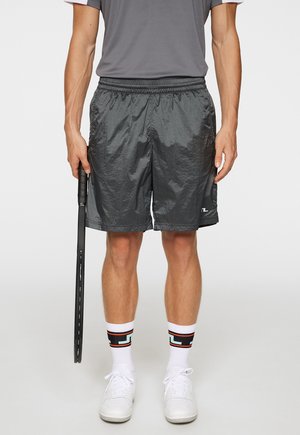 Sorte letvægts atletikshorts med elastisk talje, parret med hvide sokker med et multikolor geometrisk mønster og hvide sneakers.
