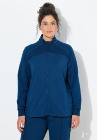 Chaqueta azul marino con cremallera, confeccionada en un material suave, con detalles de ribete negro y cuello alto, que cuenta con mangas largas y bolsillos laterales.