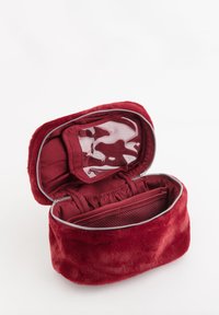 Rødt kosmetiktaske med pelskstruktur og sølvlynlås, som indeholder en indvendig lomme, et netrum og et klart opbevaringssektion.