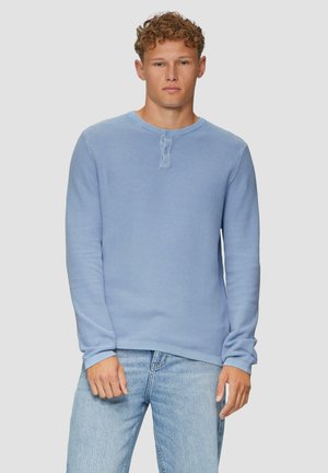 Chemise henley à manches longues bleu clair en tissu texturé, avec un col rond et une patte de boutonnage à deux boutons au centre.
