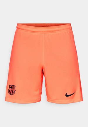 Oranži sporta šorti, kas izgatavoti no viegla auduma, ar melnu Nike logo un Barselonas ģerboni apakšējā kreisajā pusē.