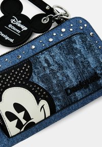 Portafoglio in denim con design di Topolino in pelle nera, borchie argentate e etichetta Disney. Predominantemente blu con motivi testurizzati.