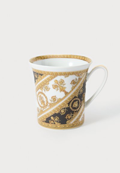 Taza de porcelana con patrones decorativos en dorado y negro, que presenta una forma curvada y un asa. El diseño incluye motivos intrincados y detalles.