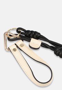 Sangle tressée noire avec accents en cuir crème, dotée d'une boucle métallique dorée et d'un mécanisme de libération rapide. Matériaux texturés et durables.