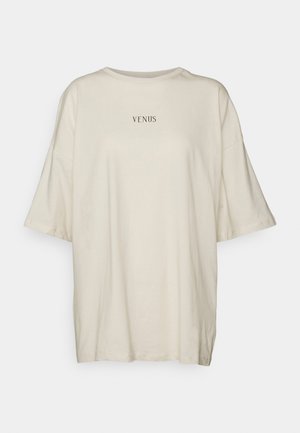 Cream-colored oversized t-shirt made of soft fabric, featuring a round neck and short sleeves. Centered black text reads “VENUS.”