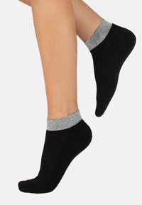 Calzini neri alla caviglia con un polsino metallico argentato a coste, texture liscia e forma classica, che enfatizzano il comfort e i dettagli discreti.