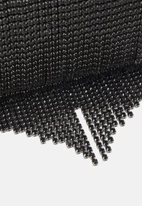 Gros plan sur un tissu en maille de strass noirs avec des pierres brillantes et facettées disposées en motif quadrillé, avec quelques fils lâches sur le bord.