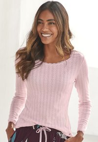 Lichtroze langemouwshirt met een gegolfde halslijn, gekenmerkt door verticale ribbeltextuur en subtiele complexe patronen. Gemaakt in combinatie met gemusterde onderkleding.