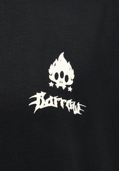 Άσπρο καλλιτεχνικό κρανίο με φλόγες και τρεις υποδοχές ματιών πάνω από γκράφιτι κείμενο σε φόντο μαύρου υφάσματος.