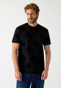 Sort t-shirt med et tekstureret mønster af mørke logoer. Crew neck-design med korte ærmer, lavet af blødt bomuldsstof.