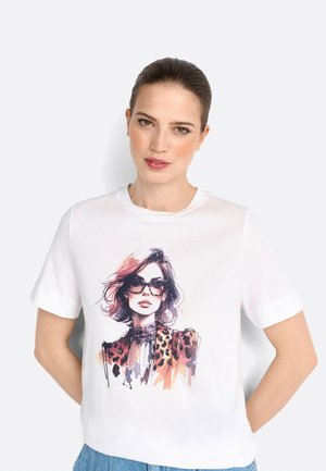 T-shirt en coton blanc avec une illustration colorée d'une femme portant des lunettes de soleil et un col en imprimé léopard. Manches courtes, coupe décontractée.