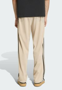Beige trainingsbroek met zwarte zijstrepen, gemaakt van lichtgewicht stof; losse pasvorm met een rechte pijp en elastische tailleband.
