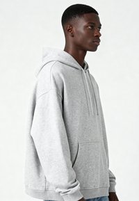 Sivá mikina s kapucňou z mäkkého materiálu, s prednou kapsou, šnúrkou na kapucni a kanalíkovými manžetami. Voľný strih s jednoduchým dizajnom.