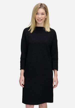 Abito nero in tessuto texturizzato con vestibilità morbida, scollo rotondo e maniche a tre quarti, caratterizzato da un design al ginocchio. Semplice e versatile.